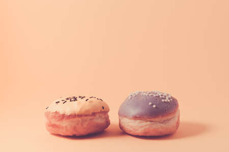 donuts isolated on pink background/Donuts in glaze decorated with dark chocolate sticks and balls on pink background, selective focusの写真素材