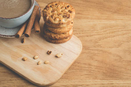 cinnamon sticks, cookies with nuts and a cup of cappuccino/cinnamon sticks, cookies with nuts and a cup of cappuccino on a wooden tray. Top view and copy spaceの写真素材