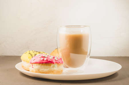 donuts in glazes and a glass of a cappuccino/donuts in glazes and a glass of a cappuccino on a white tray. Selective focusの写真素材