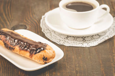 Eclairs with chocolate and a coffee cupの写真素材