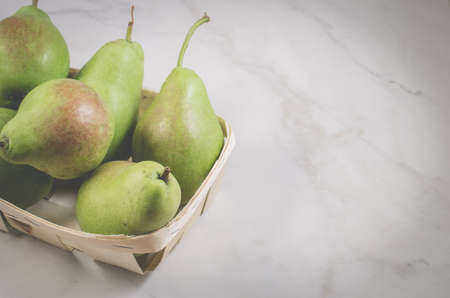 ripe pears in a wattled box/ripe pears in a wattled box on a white marble background, top view and copy spaceの写真素材