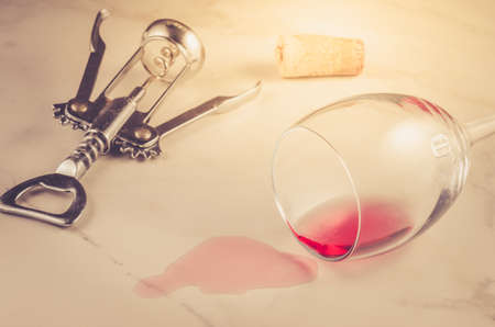 poured wine glass and corkscrew on marble background/poured red wine glass and corkscrew on marble background. Selective focusの写真素材