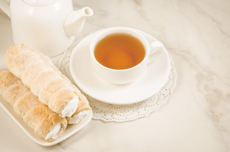 cake a tubule with white cream and tea cup on a white marble background