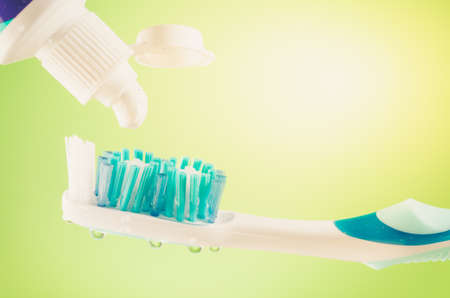 Toothpaste squeezed from tube onto brush on a green background, close upの写真素材