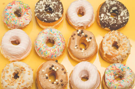 Colorful donut pattern on yellow background. Sweet food concept. Top viewの写真素材