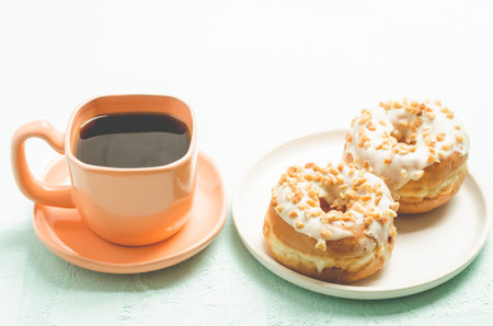 Ð¡offee break. Orange cup with coffee and a plate from donata in white glaze with nuts