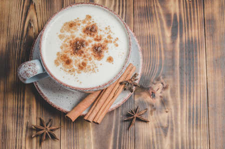 Eggnog. Traditional christmas cocktail in a cup and cinnamon sticks and anise on a woodenの写真素材
