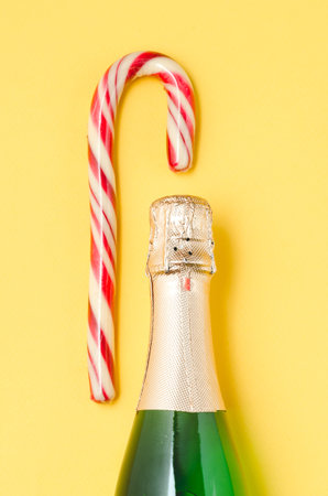 Holiday Bottle of champagne and candy canes over yellowの写真素材