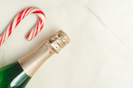 Holiday Bottle of champagne and candy canes over whiteの写真素材