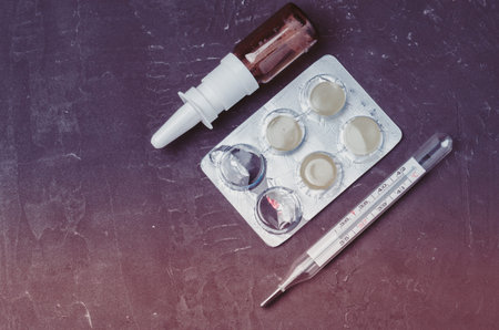 Drug spray bottle, pills packages and thermometer on black background/Drug spray bottle, pills...