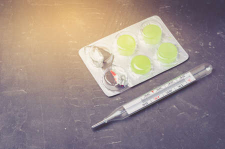 Two pills packages and thermometer on black background/ Packages of pills and thermometer are placed on a black background. Top view and copyspaceの写真素材