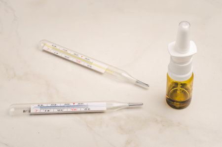 Drug spray bottle and thermometers on white background/Drug spray bottle and thermometers are placed...