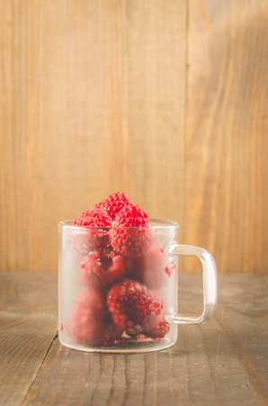 frozen red raspberry used in a glass cup/frozen red raspberry used in a glass cup on a wooden table,...