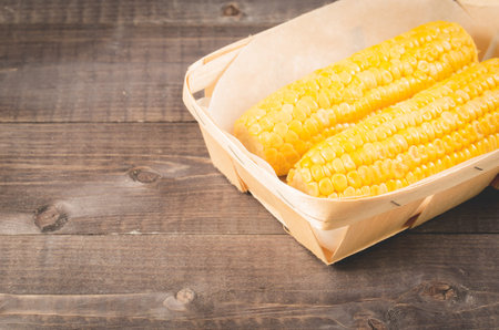 Corn. Appetizing boiled corn in a small basket on a wooden table. Copy space.の写真素材