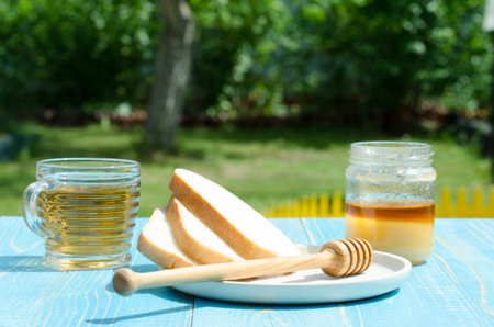 tea with honey and the cut white pastries slices on a wooden blue table background. Tea with honey in a summer gardenの写真素材