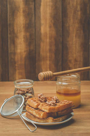 Wafers. Homemade pastries. Wafers with honey and walnut with a sieve on a wooden table.の写真素材