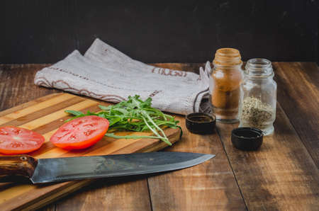 Salad. It is fresh the sliced tomatoes with arugula and seasonings in a white bowl. On a wooden table. Selective focusの写真素材