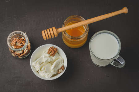 Healthy breakfast background. Honey, milk, cottage cheese and walnut on a stone background. Top view.の写真素材