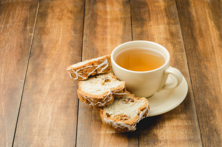 Tea cup and pastries piece on wooden table. Breakfast. Selective focus