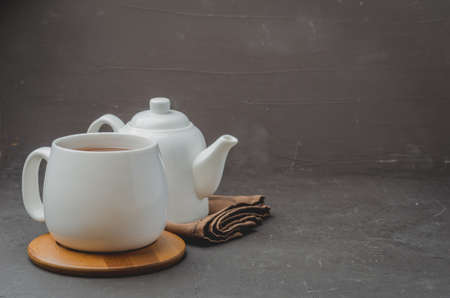 white cup of tea and teapot on a black stone background, copyspace and selective focusの写真素材