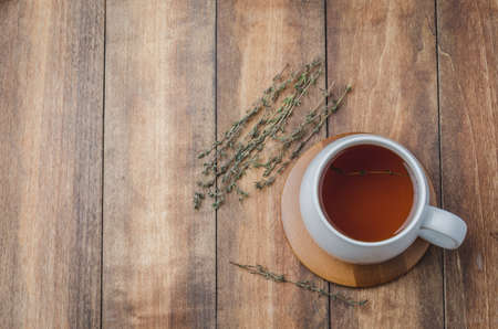 Thyme herbal tea in a white cup on a wooden table. View from above, space for a textの写真素材