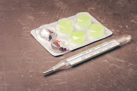 pills packages and thermometer on black background/ Packages of pills and thermometer are placed on...