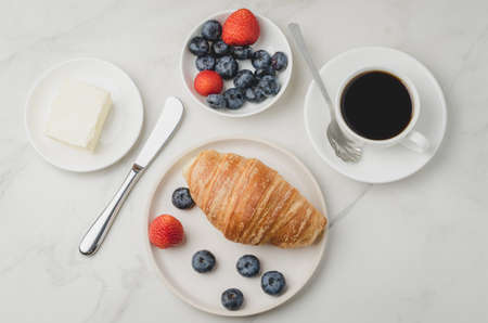 Delicious breakfast with fresh coffee, fresh croissants and berries on a white table. Top view. の写真素材