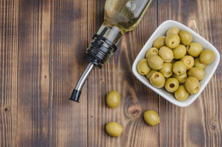 Fresh olives and oil in bottle on wooden background with copyspace. Top view. Organic olive oil conceptの写真素材