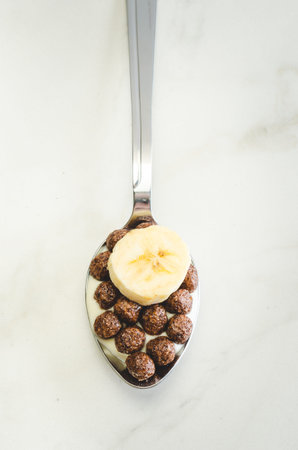 Healthy Breakfast. Yogurt, flakes and banana pieces in a spoon. Top view, flatlay