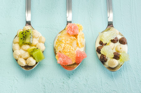 Healthy Breakfast. Yogurt, flakes and fruit in spoons on a blue background. Top view, flatlay