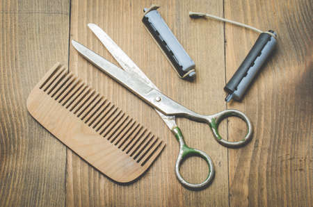 hairbrushes, curlers and a scissors on a wooden board, top viewの写真素材