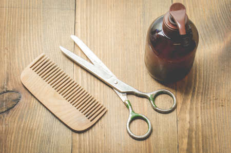 barbershop concept. Hairbrushes, sprayer and a scissors on a wooden background, top viewの写真素材