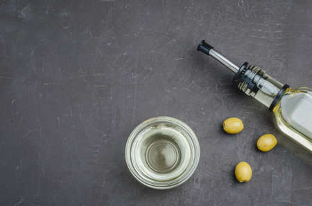 olive oil on glass bottle with glass bowl on a dark background with copy space. Top view. Template design with sample textの写真素材