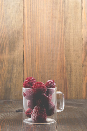 frozen raspberry used in a glass cup/frozen raspberry used in a glass cup on a wooden background