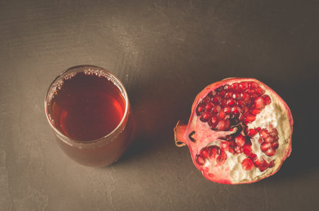 Pomegranate fruit and juice in glass/Pomegranate fruit and juice in glass on dark background, top viewの写真素材