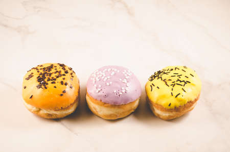 Donuts. Assorted donuts lying on a white table on purple background, top view. Ð¡oncept sweet food.の写真素材