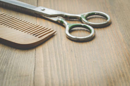 scissors and comb on old wooden background, selective focus. Barbershop conceptの写真素材