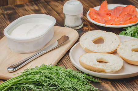 cooking of a food with round toast with cheese, red fish, tomatoes and vegetables/Healthy food with round toast, red fish, vegetables and cheese on wooden table.の写真素材