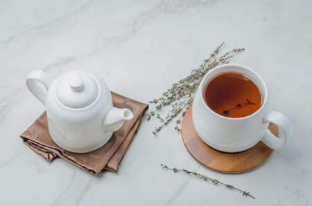 Thyme herbal tea, view from high angle on white cup with tea and kettleの写真素材