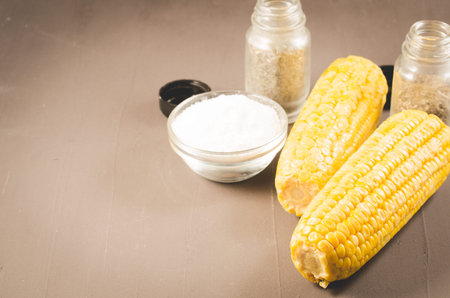 Corn. Boiled corn with salt and seasonings on a dark table. Top view and copy space