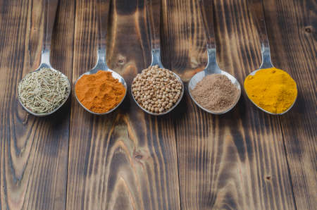 various spices in spoons on a wooden table, top view and copyspaceの写真素材