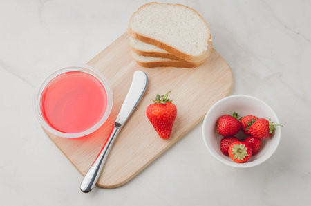 Strawberry jam. Making sandwiches with strawberry jam. Top view. Bread and strawberry jam on a white...