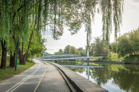 Bike path in the park with green beautiful trees along the river. Beautiful summer landscape.の写真素材