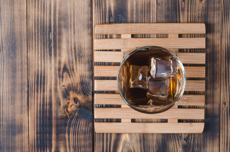 Glass of cognac with ice cubes on a wooden table/Glass of cognac with ice cubes on a wooden table. Top view, copyspaceの写真素材