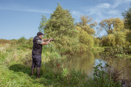 Man fishing with a rod on the river bank on a sunny day.