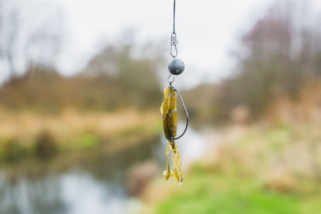 Khakki silicone lure for fishing. Silicone bait for fishing hanging on a hook on the background of...