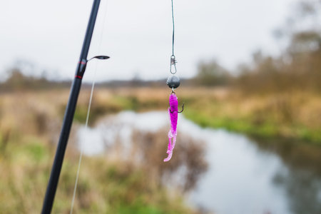 Silicone bait for fishing hanging on a hook on the background of the river.の写真素材