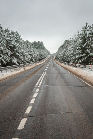 Snow covered asphalt road in the forest. The road through the winter forest.