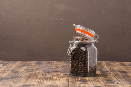 Coffee in a glass jar on a wooden table. Selective focus. Coffee grains in an open glass jar on a wooden table and background for text.の写真素材