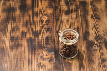 Coffee in a glass jar on a wooden table. Copy space. Coffee grains in an open glass jar on a wooden table.の写真素材